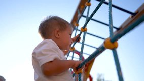 child plays on the playground. concept of happy childhood and loving family. a child smiles joyfully and climbs a ladder on lifestyle a playground, the glare of the sun in the background - Powered by Shutterstock - Get 15% off with code: PIKWIZARD15