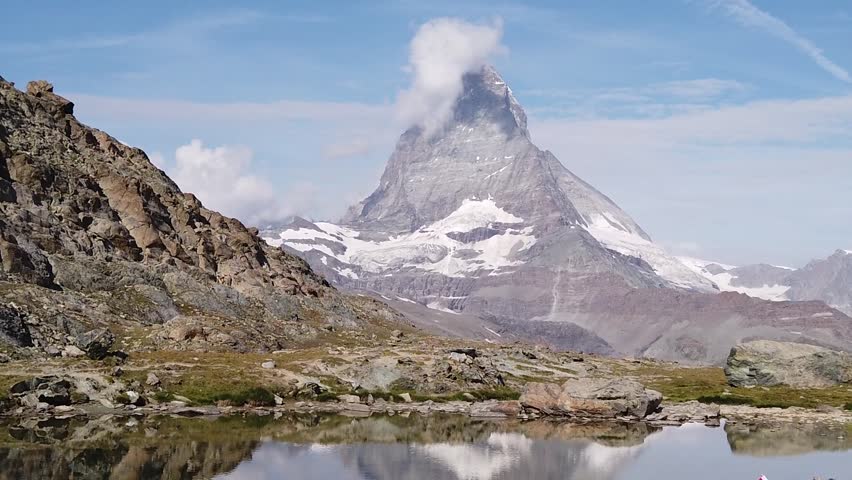 SLOW MOTION: Woman with Swiss flag at Mount Matterhorn or Mont Cervin, reflected on Riffelsee Lake. Tourism in Zermatt,Canton of Valais, Switzerland. Scenic landscape of popular tourist attraction Royalty-Free Stock Footage #3397537991