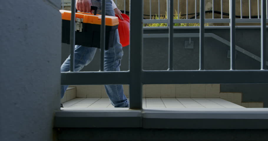 Builder legs walking downstairs with construction tools box in hands. Worker carry equipment walking down staircase on way to location Royalty-Free Stock Footage #3397744677