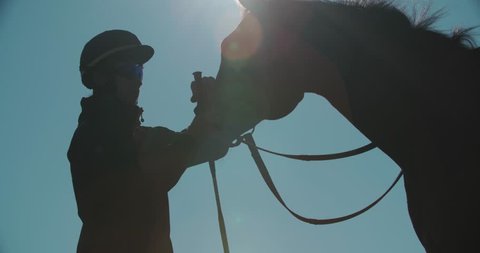 silhouette of a jockey calms aggressive race horse before a competition
