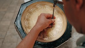 Master, tinsmith, creates a pattern on a brass dish or tray. Close-up. Copper master, hands detail of craftsman at work. Uzbekistan, Bukhara - Powered by Shutterstock - Get 15% off with code: PIKWIZARD15