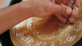 Master engraves patterns on a metal plate. Close-up, handmade, tinsmith, working with hammer during hand stamping or engraving decoration pattern on metal tray. Copper master, hands detail of - Powered by Shutterstock - Get 15% off with code: PIKWIZARD15
