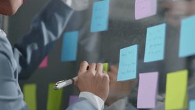 Businesswoman in suit write business strategy on Post-it sticky notes and paste on the board for business planning and marketing. - Powered by Shutterstock - Get 15% off with code: PIKWIZARD15