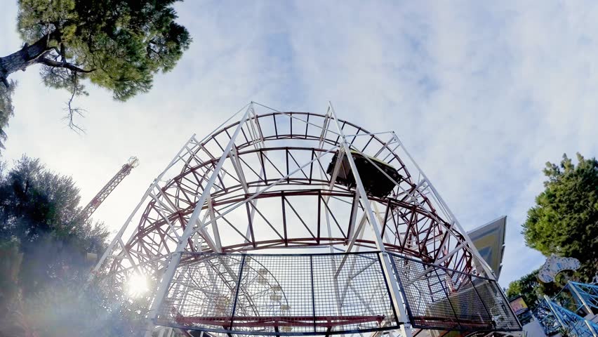 A running roller coaster with screaming people aboard having fun, seen from below. Emotions of a happy day.
