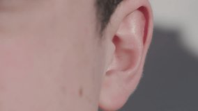 Man putting earphone into ear to listen to music and then taking them out again