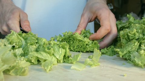 Man is cutting a green salad in the kitchen