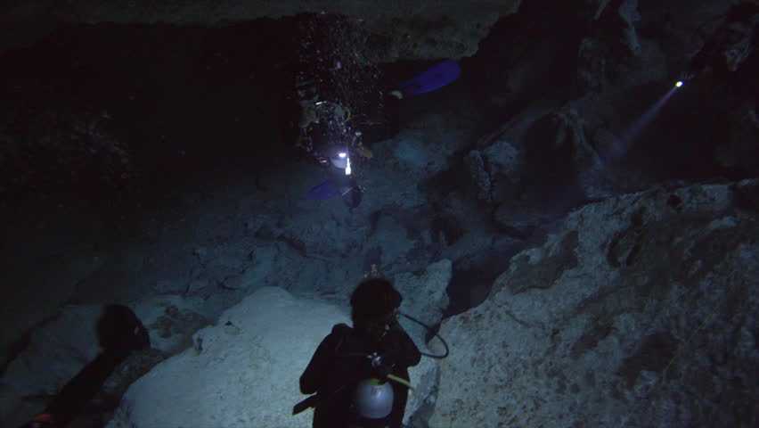  group of divers underwater with flashligh make a photo in cenote with stalagmites  Royalty-Free Stock Footage #33980797