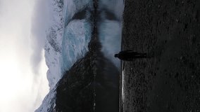 Man Walks towards Portage Glacier. Portage Lake, Reflection and Snow-Capped Mountains on Sunny Day. Alaska, USA. Aerial View. Vertical Video - Powered by Shutterstock - Get 15% off with code: PIKWIZARD15