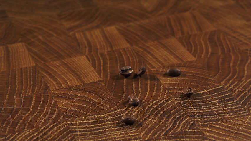 Coffee beans pouring slow motion filmed at 250fps on wooden background