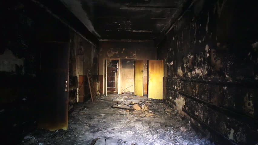 The interior or dark corridor of the burnt down building after the fire, is illuminated at night by a lantern, burnt furniture, walls in soot Royalty-Free Stock Footage #33984505