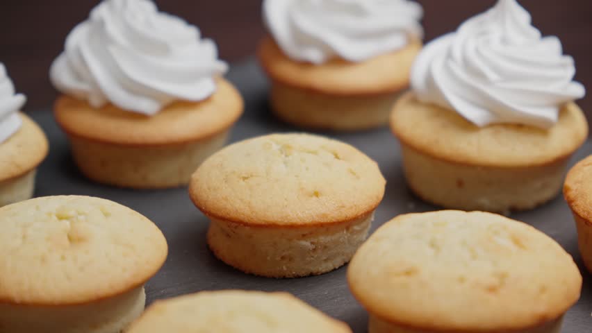 Decorating cupcake with white cream. Cooking delicious homemade cakes. Home bakery concept. Decorating muffins with cream. Close-up in 4K, UHD