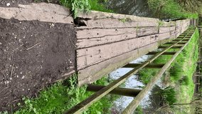 Vertical video. Personal point of view, POV walking on an old rotten and unsafe wooden footbridge.