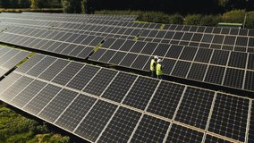 Drone shot of engineers inspecting solar panels in field generating renewable energy - shot in slow motion - Powered by Shutterstock - Get 15% off with code: PIKWIZARD15