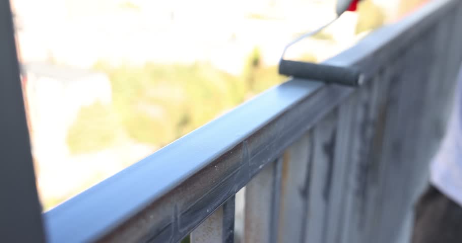 Master painter paints metal railings with gray paint on balcony. Roller for painting metal pipes Royalty-Free Stock Footage #3398550705
