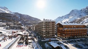 Panoramic aerial drone scenic view at ski slopes, mountain skiing and popular resort town. Italian ski resort in Alps in Aosta Valley in winter.