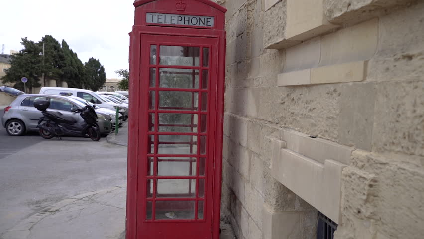 Classic red telephone booth. A girl enters a telephone booth.