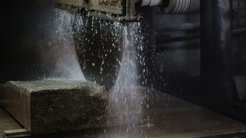 Circular saw cutting of Huge stone block of limestone. Granite processing in manufacturing. Cutting granite slab by a circular saw. Use of water for cooling