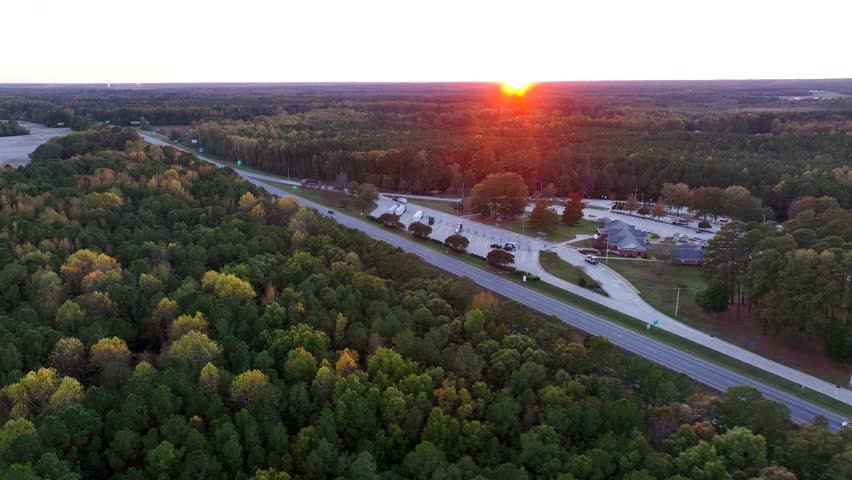 Rest stop along an interstate highway in Appalachia, USA during autumn sunset. Aerial view of the state line and cotton field surrounded by woodlands.