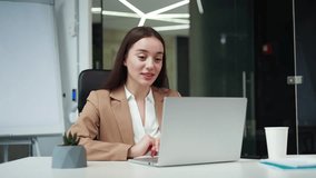 Attractive caucasian businesswoman in formal wear gesturing with hands during online conversation on modern laptop. Skilled female project manager having video call with colleagues at workplace.