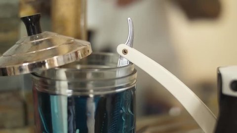 barber removing a razor blade from a disinfectant jar slow motion