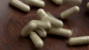 Herbal supplement vitamin capsules falling into a wooden bowl. Prescription natural pills. Herb medicine tablets - Powered by Shutterstock - Get 15% off with code: PIKWIZARD15