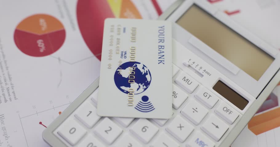 A white plastic bank card lies on a calculator, a close-up. Favorable conditions of deposit, credit history