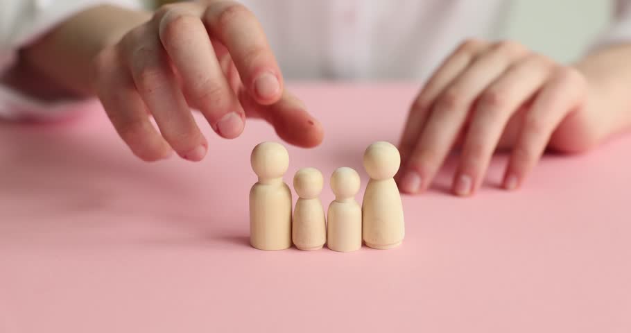 Female hands and wooden dolls on a pink background, close-up. The concept of the collapse of the family Royalty-Free Stock Footage #3398895893