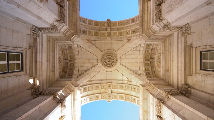 Famous Augusta arch - Arco da Rua Augusta, situated Commerce Square - Praça do Comércio - Downtown Lisbon. Portugal. Camera spinning under the arch. Beautiful architecture details. Blue sky.  Royalty-Free Stock Footage #3398906565