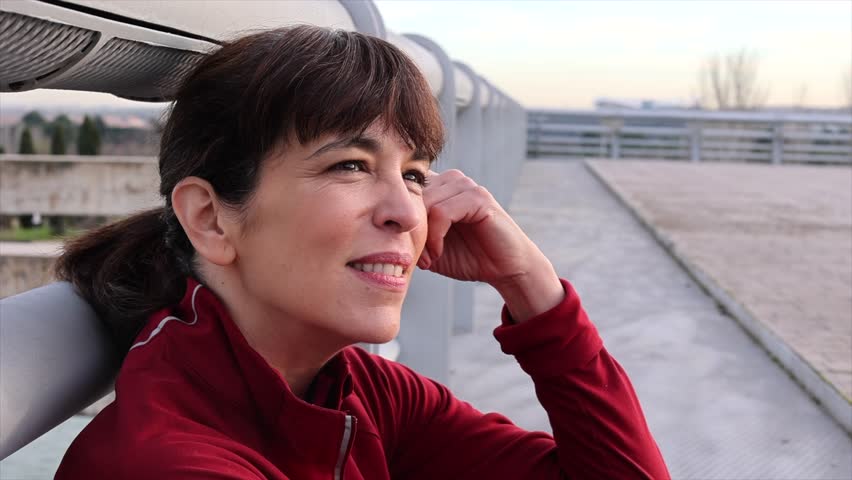 close up portrait of mature adult woman resting from her sports activities while contemplating the horizon happy