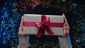 Female hands with beautiful gift box with ribbon on shining glitter decorations. - Powered by Shutterstock - Get 15% off with code: PIKWIZARD15