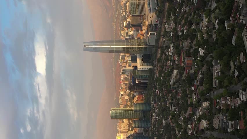 Santiago City at Sunset and Andes Mountains. Aerial View. Chile. Drone Flies Backwards and Upwards. Vertical Video