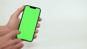 Mobile Phone With Green Mock-up Screen In Men's Hands On White Background. Man Performing Swipe, Scroll, and Tap Gestures to Smartphon Display