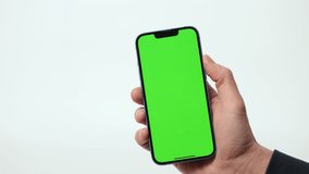 Close Up of Mobile Phone With Green Mock-up Screen In Men's Hands On White Background. Man Using Smartphone, Browsing Internet, Social Networks