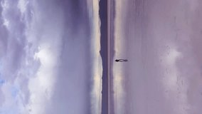 Man Standing and Looking at Uyuni Salt Flats. Aerial View. Altiplano, Bolivia. Rainy Season. Reflection on Water. Wide Shot. Dramatic and Stormy Clouds. Solo Traveling Concept. Vertical Video - Powered by Shutterstock - Get 15% off with code: PIKWIZARD15