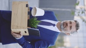 Vertical Video. Depressed Caucasian Male Office Worker Walking Near Business Center Building with Box of Personal Stuff. Businessman Lost Job. Fired Man Going Outdoor. Depressed Jobless Person - Powered by Shutterstock - Get 15% off with code: PIKWIZARD15