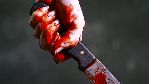 Bloody knife. Hand holds a bloody knife