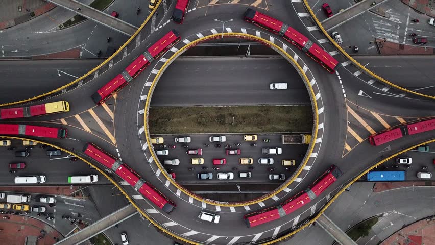 Aerial drone shot of Roundabouts in Bogota, Colombia, Latin America. Traffic in Bogota, Transmilenio. Dedicated busway on the top level. Famous roundabout full of red buses. High quality 4k footage. Royalty-Free Stock Footage #3399312295