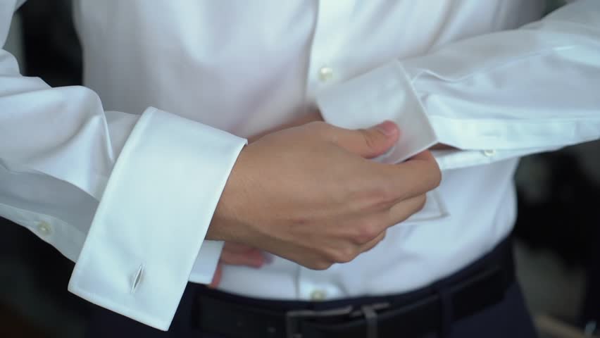 Man button up his shirt sleeves, wears white shirt and cufflinks. Person wears a white shirt and cufflinks. The groom is going to the wedding. Royalty-Free Stock Footage #3399317877
