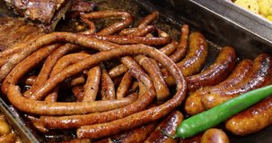 Close-up of homemade pork and beef sausages fried in boiling oil in a hot frying pan. 4k video