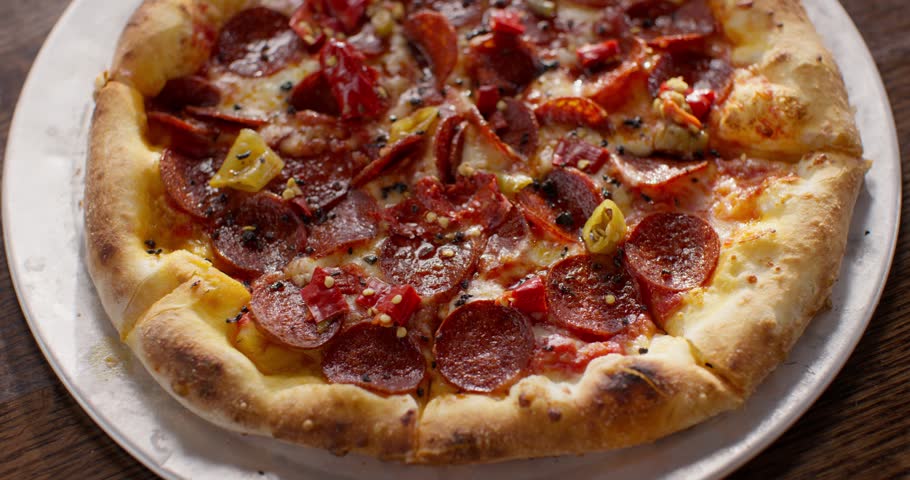 Closeup of plate with tasty pizza. Freshly baked pizza located at table. Italian pizza. Food and drink concept. Big portion. Ingredients. Prepared pizza with salami, peppers and cheese.