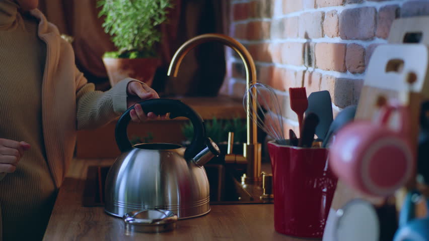 Amazing kitchen design rustic stile capturing video closeup lady take the kettle and add some water tap to boil water for a hot drink