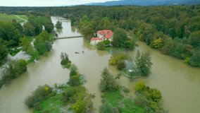 AERIAL: Picturesque water castle on an island in the middle of a flooding river. Incredible view above rising waters of muddy river Krka overflowing its banks after abundant rainfall in autumn season.