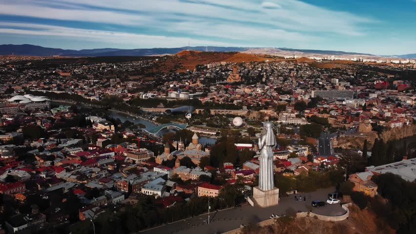Tbilisi, Georgia - October 1, 2023: Landscape of Tbilisi and its famous statue Mother of Georgia filmed by drone at summer day. Aerial view at capital city and its streets with buildings at mountain Royalty-Free Stock Footage #3399437857