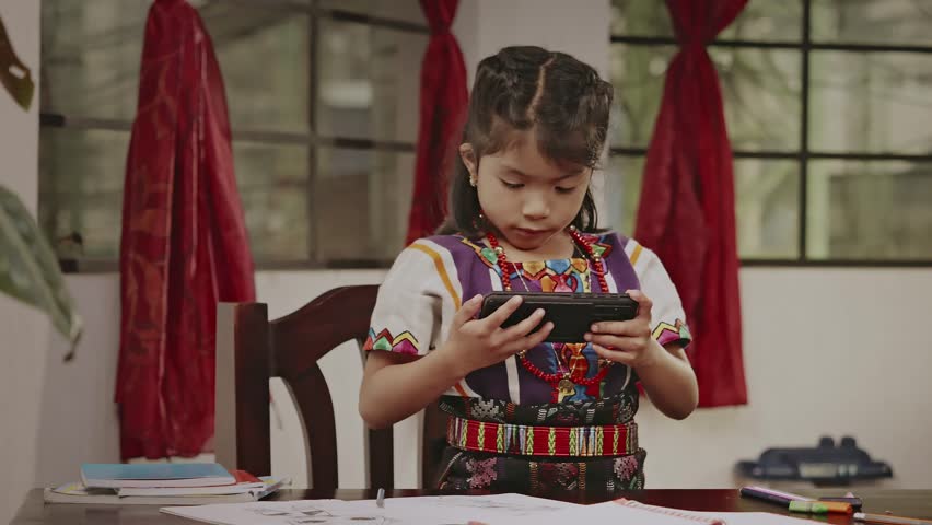 Indigenous Latina girl watches an educational video through a smartphone. Royalty-Free Stock Footage #3399503461