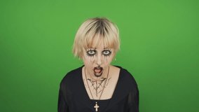 Portrait of a goth girl in black clothes and special makeup on a green background. She looks into the camera and screams sharply. Chroma key. - Powered by Shutterstock - Get 15% off with code: PIKWIZARD15