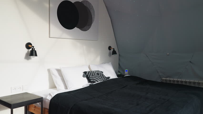 Bedroom for tourists in glamping tent. Double bed with linen blanket in tone with lamps on wall. Space for tourists looking for comfortable retreat
