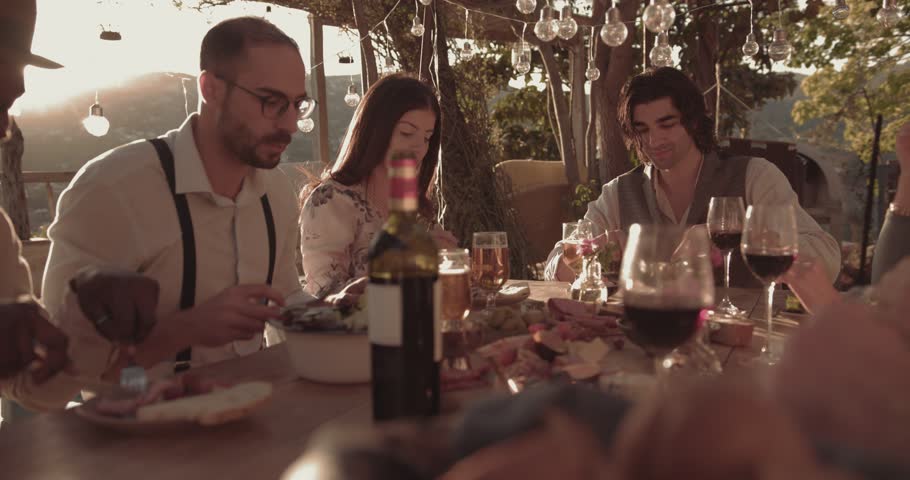 Young multi-ethnic friends and couples eating mediterranean meal at mountain village restaurant patio | Shutterstock HD Video #33996100