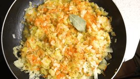 Cabbage is stewed with carrots in a frying pan. View from above. Slowmotion video. Cooking master class. Step-by-step video recipe for making stewed cabbage.
