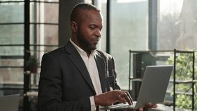 African American businessman ethnic adult 40s middle-aged business man stand with laptop in office sunny sunlight indoors. Smiling male employer CEO working computer online data analysis programming - Powered by Shutterstock - Get 15% off with code: PIKWIZARD15