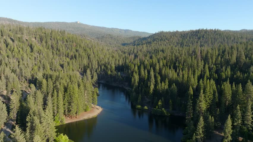 An aerial of Hume Lake reservoir surrounded by a big forest on a summer day in the Kings Canyon Sequoia National Park